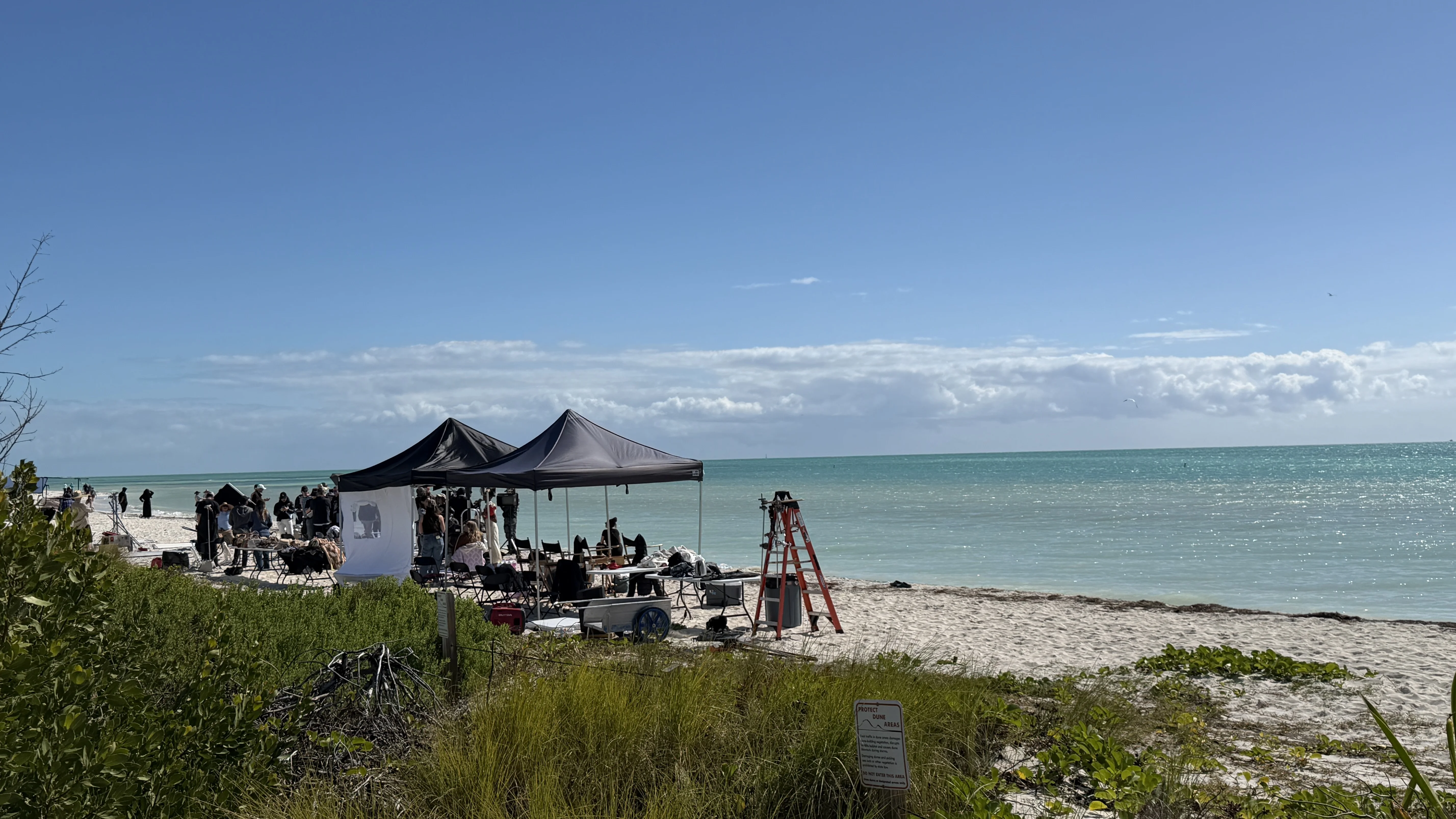Film production set on beach with tents and crew